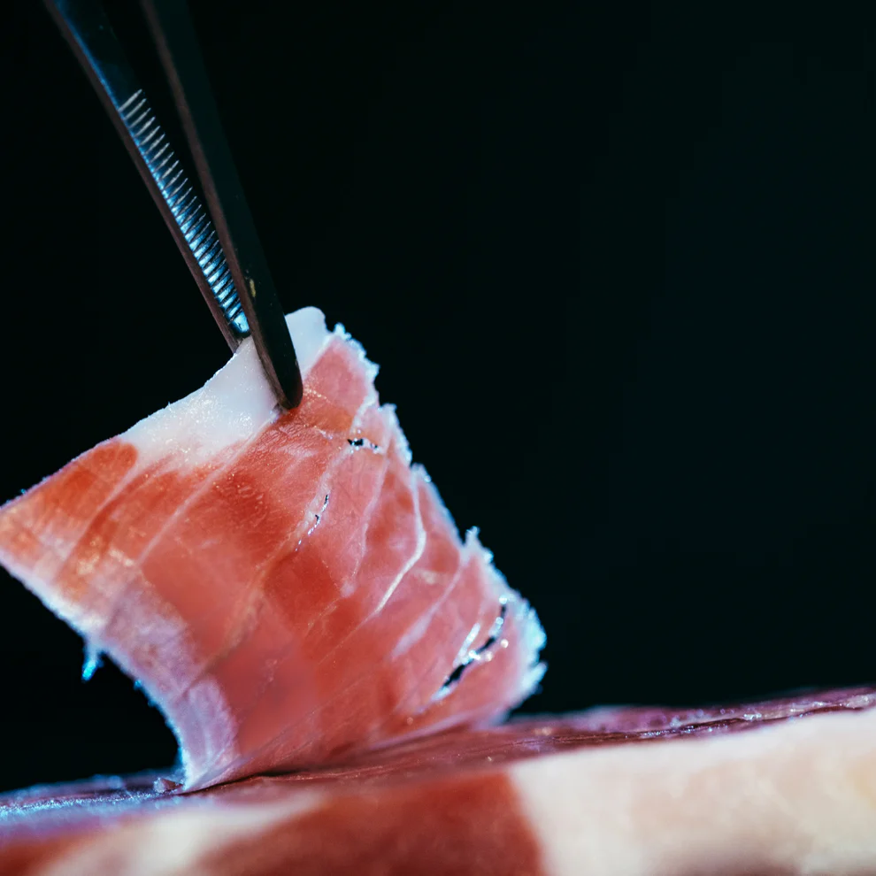 Jamón ibérico cortado loncha cogida con una pinza