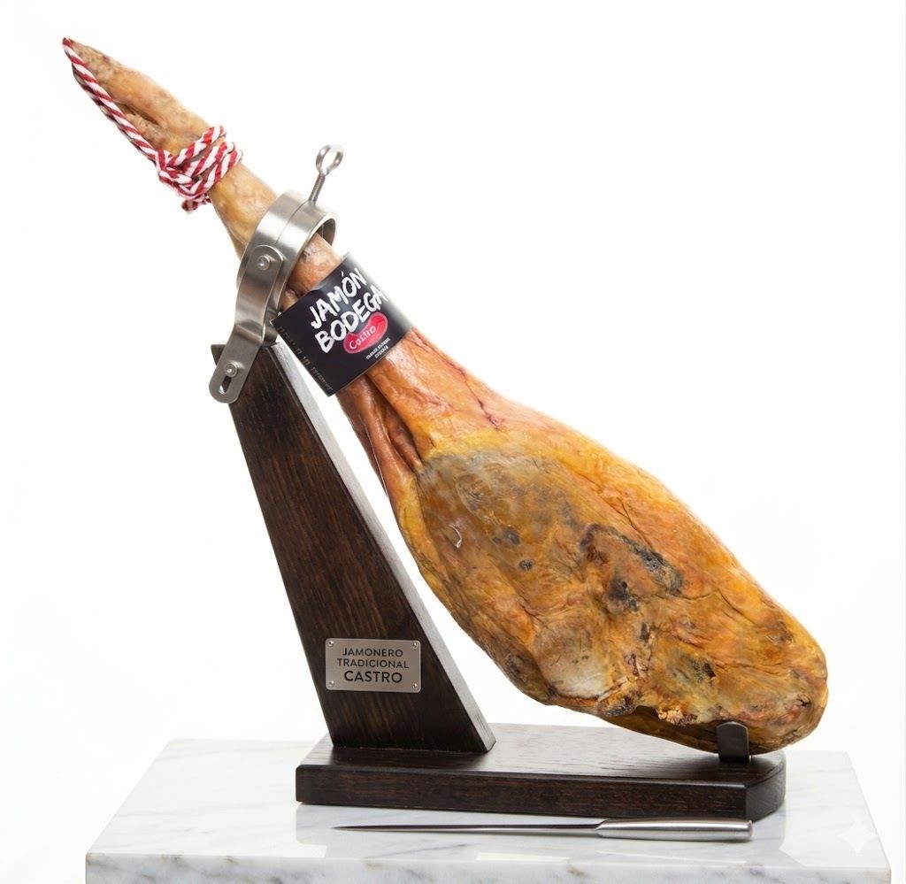 amón Bodega Reserva Castro colocado en un jamonero de madera tradicional con un cuchillo jamonero sobre una base de mármol blanca.